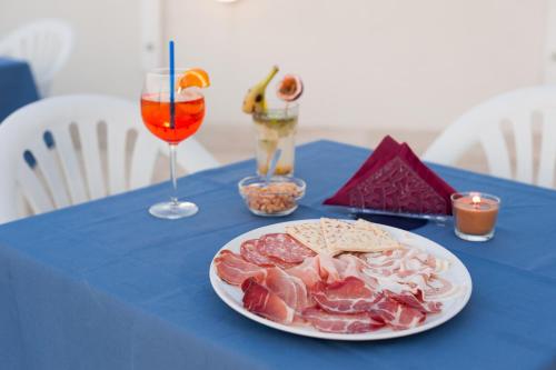 a blue table with a plate of food and two drinks at Regina Hotel e Ristorante in Punta Marina