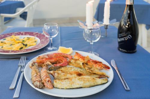 a plate of food with shrimp and a bottle of wine at Regina Hotel e Ristorante in Punta Marina
