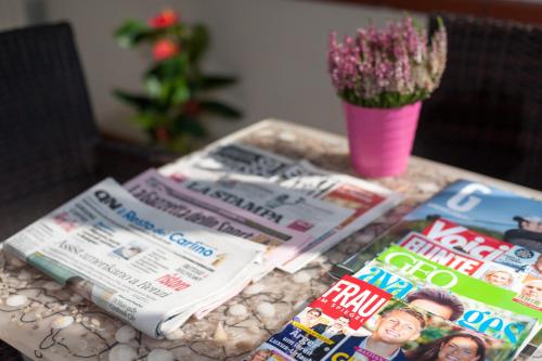 a table topped with magazines and a vase with a plant at Regina Hotel e Ristorante in Punta Marina
