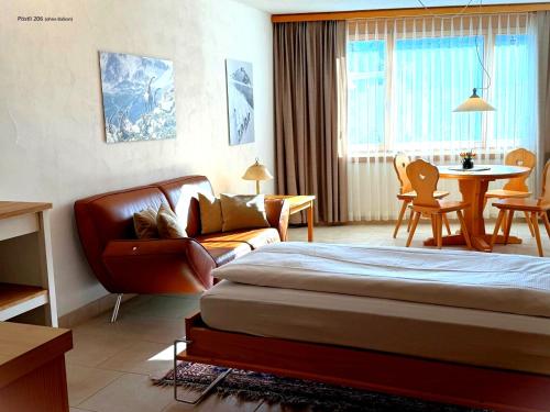 a hotel room with a bed and a couch and a table at Schweizerhaus Apartments in Maloja