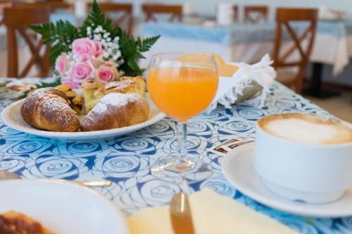 a table with a plate of pastries and a glass of orange juice at Regina Hotel e Ristorante in Punta Marina