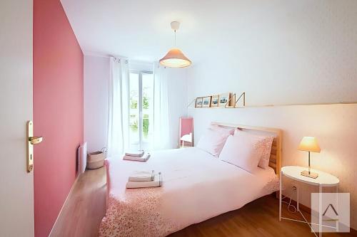 una camera da letto con un letto bianco e una parete rosa di Le Prieuré a Dinard
