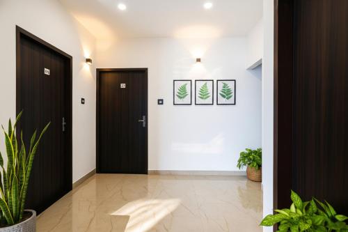 a hallway with two black doors and plants at FabHotel Paradise Inn in Indore
