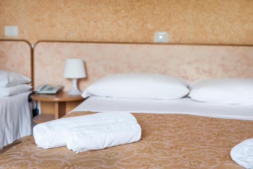 two beds in a hotel room with white pillows at Regina Hotel e Ristorante in Punta Marina