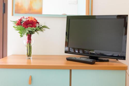 a vase of flowers sitting next to a computer monitor at Regina Hotel e Ristorante in Punta Marina