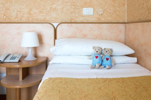 two teddy bears are sitting on a bed at Regina Hotel e Ristorante in Punta Marina