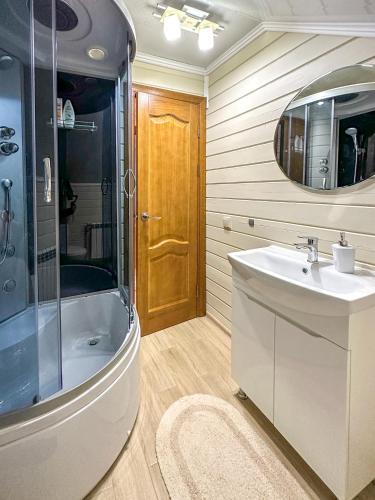 a bathroom with a sink and a tub and a mirror at KaVacottage in Krivorovnya