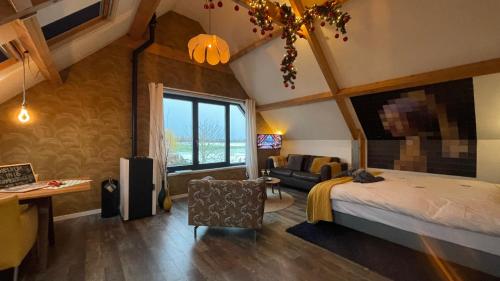 a bedroom with a bed and a desk and a couch at De Bommelerhoeve B&B & Vakantiewoning Dirkje in Poederoijen