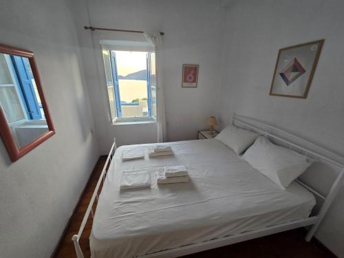 a white bed in a small room with a window at Kapsali Beach House in Kapsali