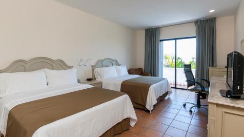 シウダード・デル・カルメンにあるHoliday Inn Ciudad Del Carmen, an IHG Hotelのベッド2台とテレビが備わるホテルルームです。