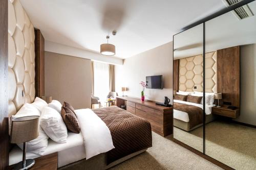 ein Hotelzimmer mit Bett und Spiegel in der Unterkunft Amsterdam Hotel Pool & SPA in Belgrad