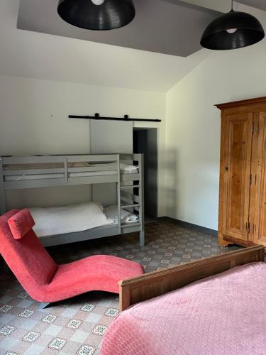a bedroom with a bunk bed and a pink chair at La Berge in La Flocellière
