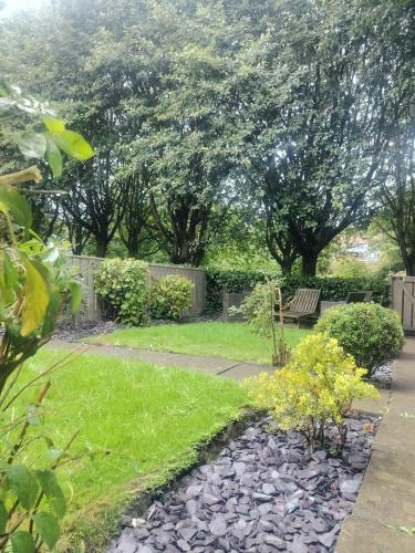 a garden with a bench and grass and trees at Your Home from Home - River bank in Cox Green