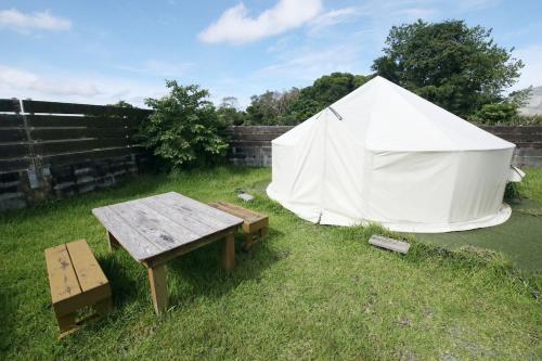 a white tent in a yard with a wooden table at halfGlamping星音 B in Nakijin
