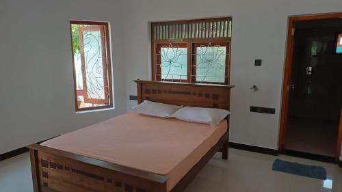 a bedroom with a wooden bed with two windows at White Umbrella - Homestay in Beruwala