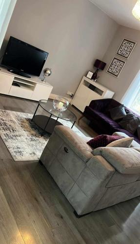 a living room with a couch and a flat screen tv at Your Home from Home - River bank in Cox Green