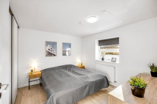 a white bedroom with a bed and a table at FeWo Lille Vidstrup in Vidstrup
