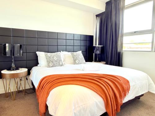 a bedroom with a large bed with an orange blanket at Chatswood Exeutive Condo - 2 Bedrooms 2 Bathrooms with King Bed in Sydney