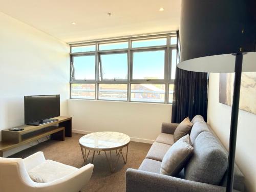 a living room with a couch and a tv at Chatswood Exeutive Condo - 2 Bedrooms 2 Bathrooms with King Bed in Sydney