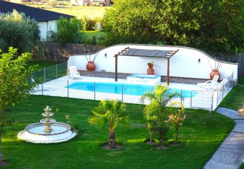 a swimming pool in a yard with two chairs and a fountain at Apart Hotel La Bodega in San Rafael