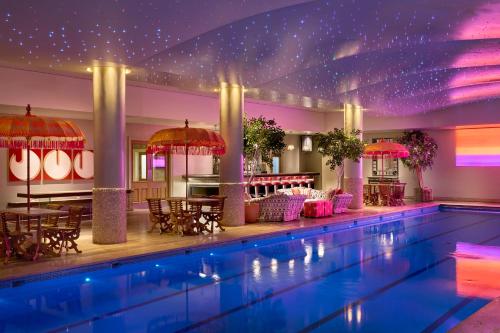a swimming pool with tables and chairs in a building at Haymarket Hotel, Firmdale Hotels in London