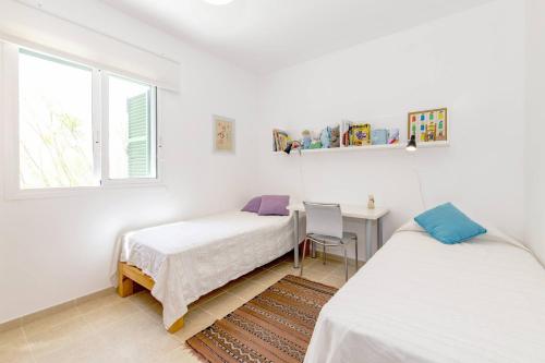 a bedroom with two beds and a desk and a window at Biniancolla Heura in Biniancolla