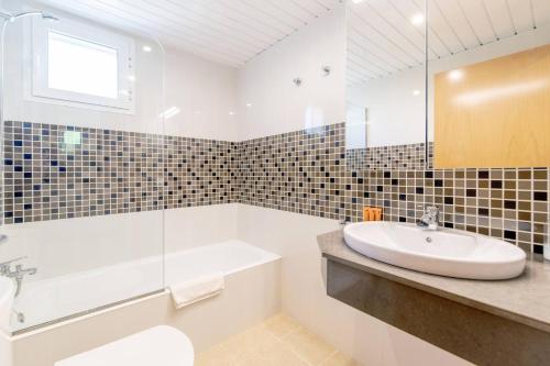 a white bathroom with a sink and a tub and a sink at Biniancolla Heura in Biniancolla