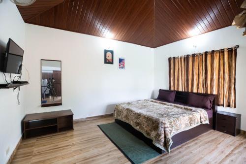 ein Schlafzimmer mit einem Bett und einem Fernseher in der Unterkunft The Nest Bettathur, Coorg in Madikeri