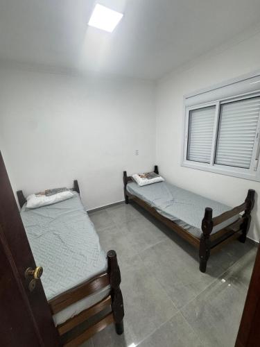 two beds in a room with a window at Casa nova em Torres in Torres