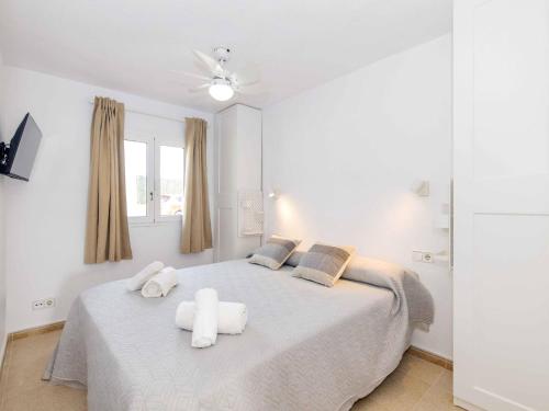 a white bedroom with a bed with towels on it at Villa Gavines down in S'Algar