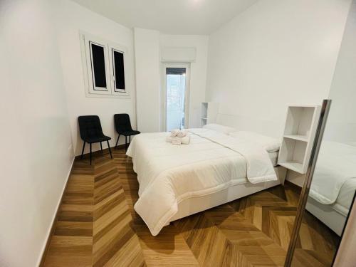 a white bedroom with a bed and two chairs at Suite Borgo 112 - Sanremo in Sanremo