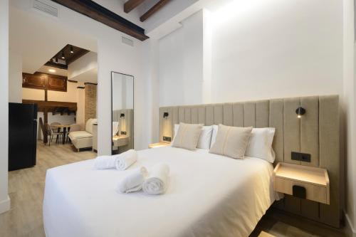 a bedroom with a large white bed with towels on it at Escolástica Suites Centro in Granada