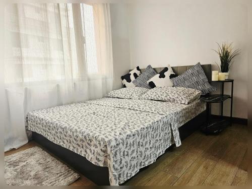 a bedroom with a bed with black and white sheets and a window at Paseo Verde Condo Unit in Las Pinas - Sleeps 2 Adults & 2 Children in Manila
