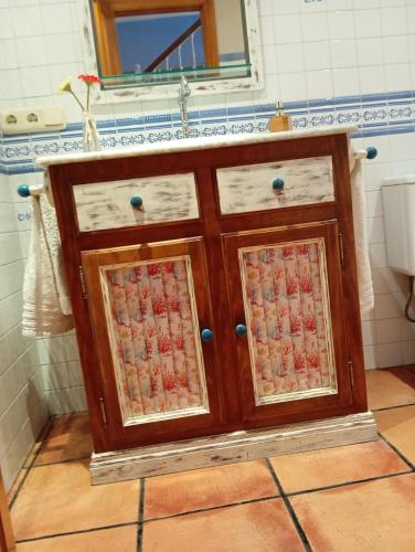 a wooden cabinet with glass doors in a bathroom at Casa Rural La Torre De Babel in Molinaseca