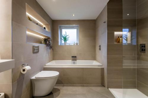 a bathroom with a tub and a toilet and a sink at Arran Shores Luxury Shorefront Apartment 8 in Lamlash