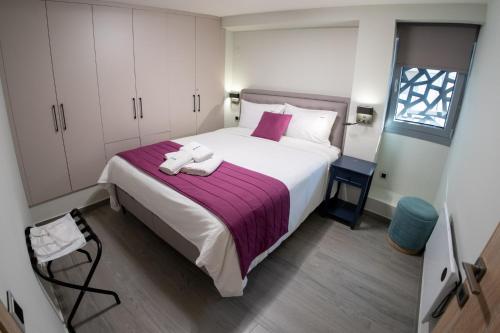 a bedroom with a large white bed with purple sheets at Pyrgiou suites in Thessaloniki