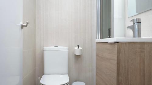 a white bathroom with a toilet and a sink at Apartamentos BCL Playa Albir in Albir