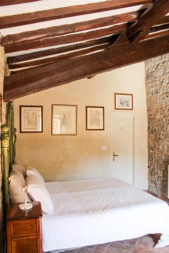 a bedroom with a white bed in a brick wall at Fattoria San Donato in San Gimignano