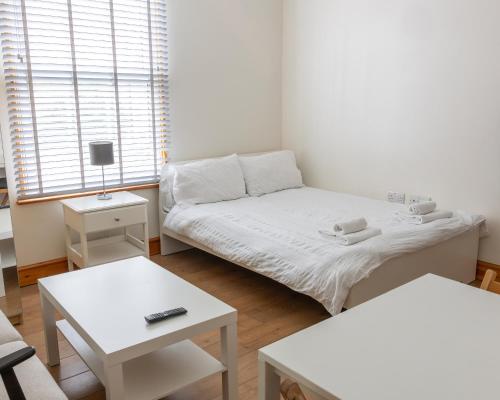 a small room with a bed and two tables at Studio apartment next to Highgate tube station in London