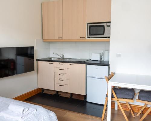 a small kitchen with a sink and a microwave at Studio apartment next to Highgate tube station in London