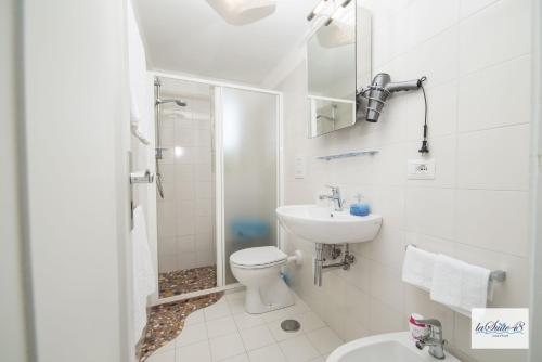 a white bathroom with a toilet and a sink at La Suite 48 in Vietri sul Mare