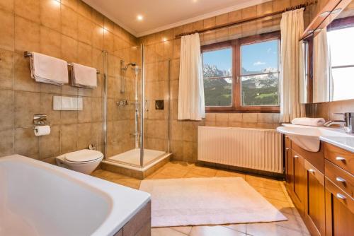 a bathroom with a tub and a shower and a toilet at Appartements Oswald in Ellmau