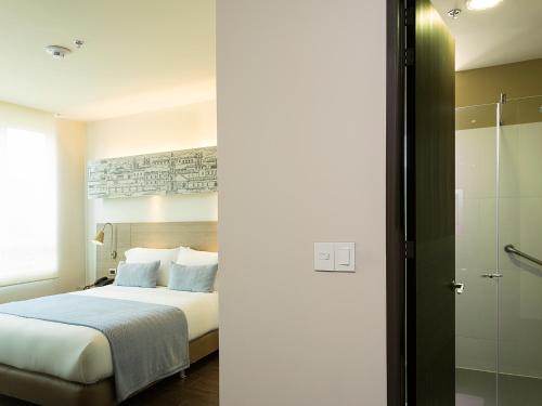 a hotel room with a bed and a shower at Hotel bh Usaquén in Bogotá