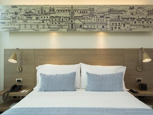 a bed with two pillows and a drawing on the wall at Hotel bh Usaquén in Bogotá