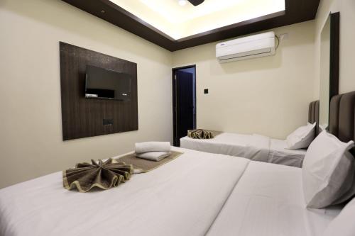 a bedroom with two beds and a tv on the wall at Hotel Bansi Palace in Dwarka