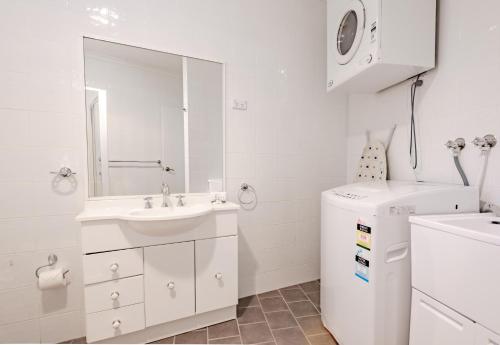 a white bathroom with a sink and a washing machine at House of Ullr in Thredbo
