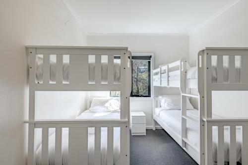 two white bunk beds in a room with a window at House of Ullr in Thredbo