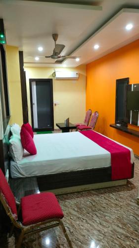 a bedroom with a bed and chairs and a tv at Hotel Rinkesh Grand in Aurangābād