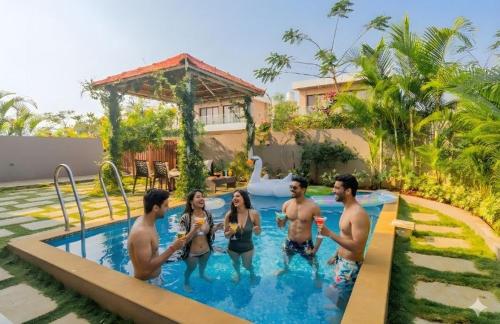 a group of people standing in a swimming pool at EKOSTAY - Trinity Villa in Karjat