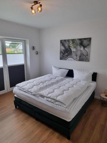 a large bed in a bedroom with avertisementatronatronstrationstrationstration at freistehendes Ferienhaus mit Sauna und Badefass in Sehestedt